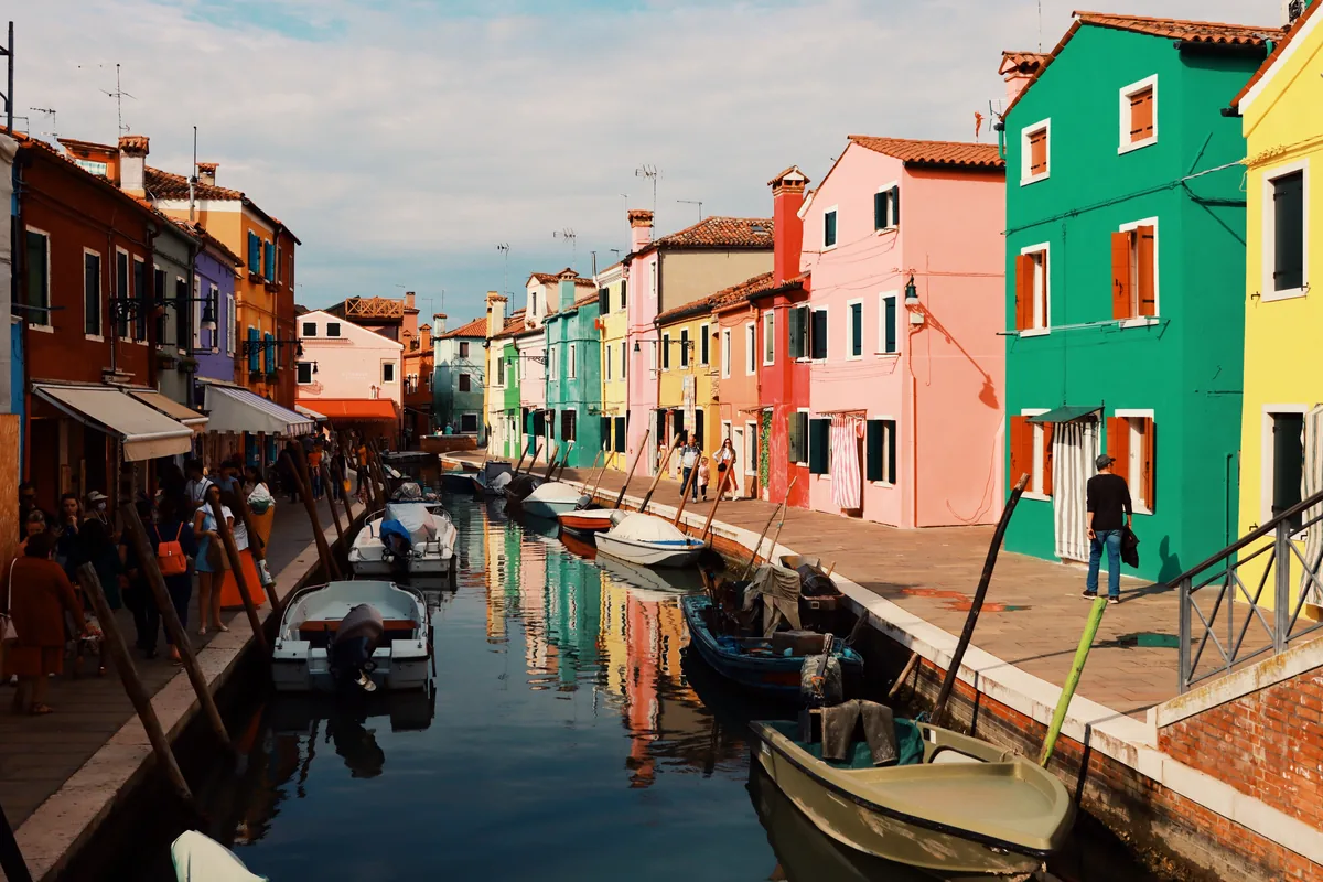 Case dai colori vivaci in rosso, verde, rosa e giallo che si affacciano su un canale a Burano, una delle isole toccate dall'itinerario della crociera.